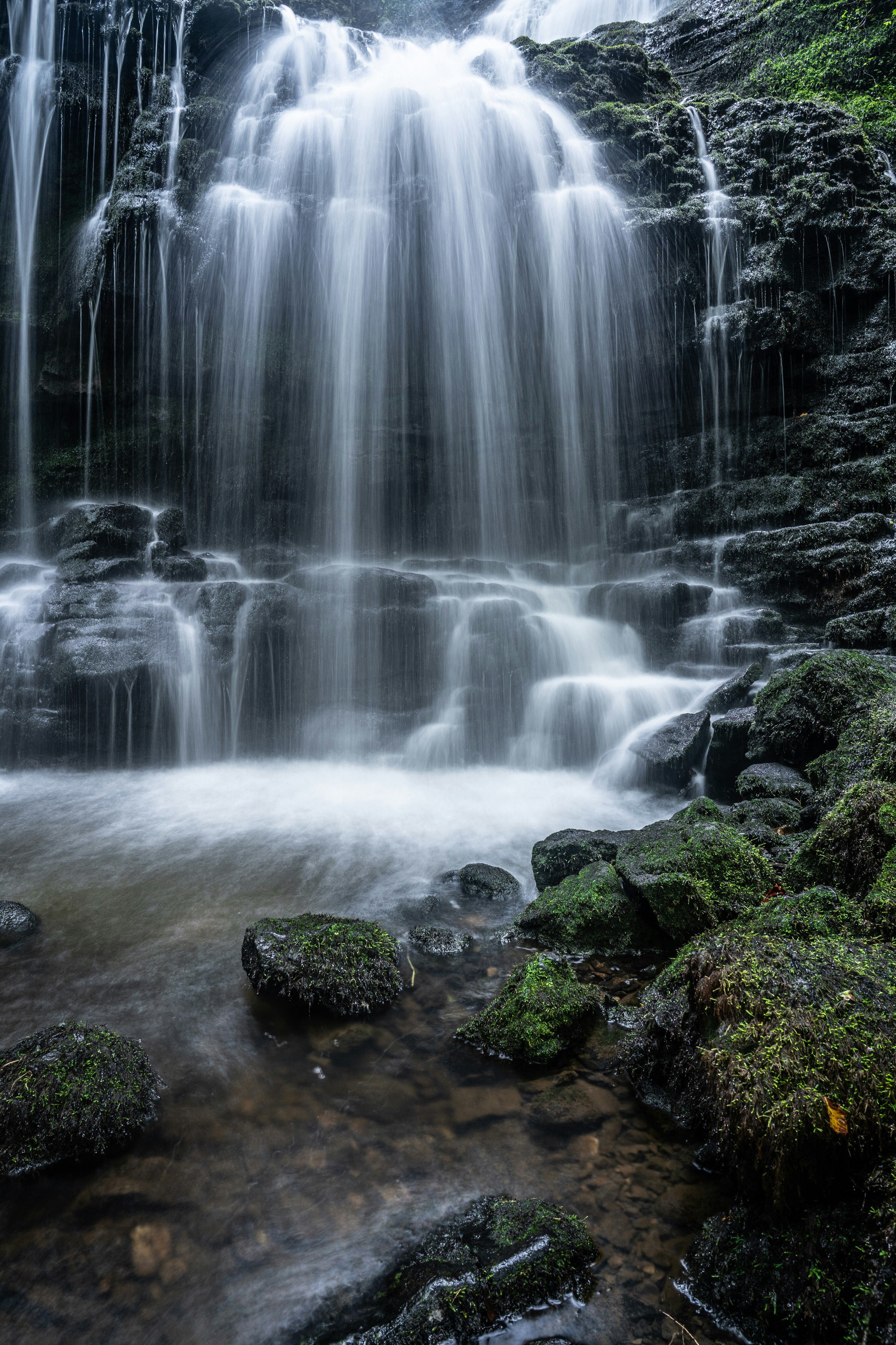 water falls on rocky shore during daytime